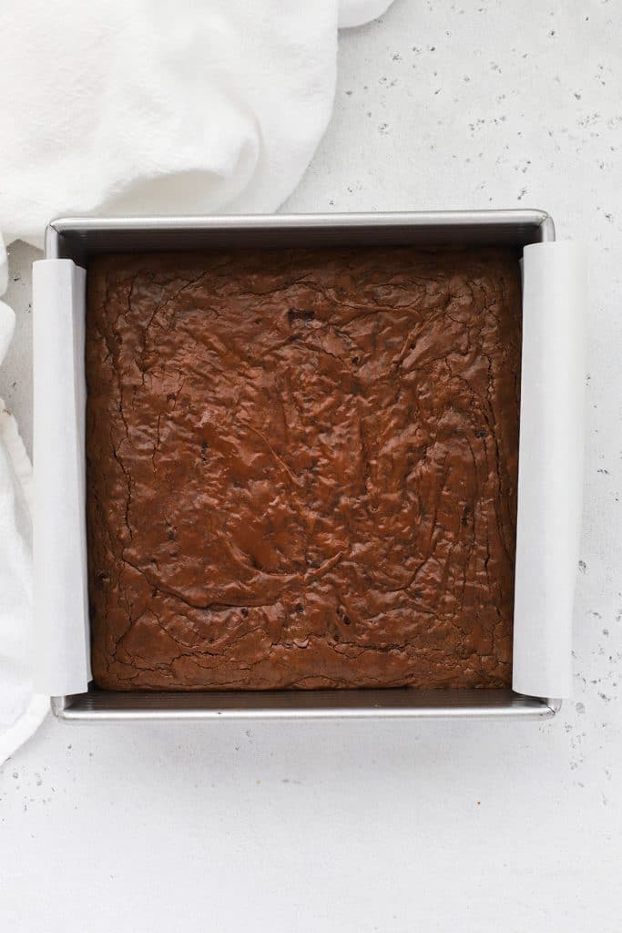 A pan of freshly baked gluten free brown butter brownies with a glossy, crackle top layer catching the light