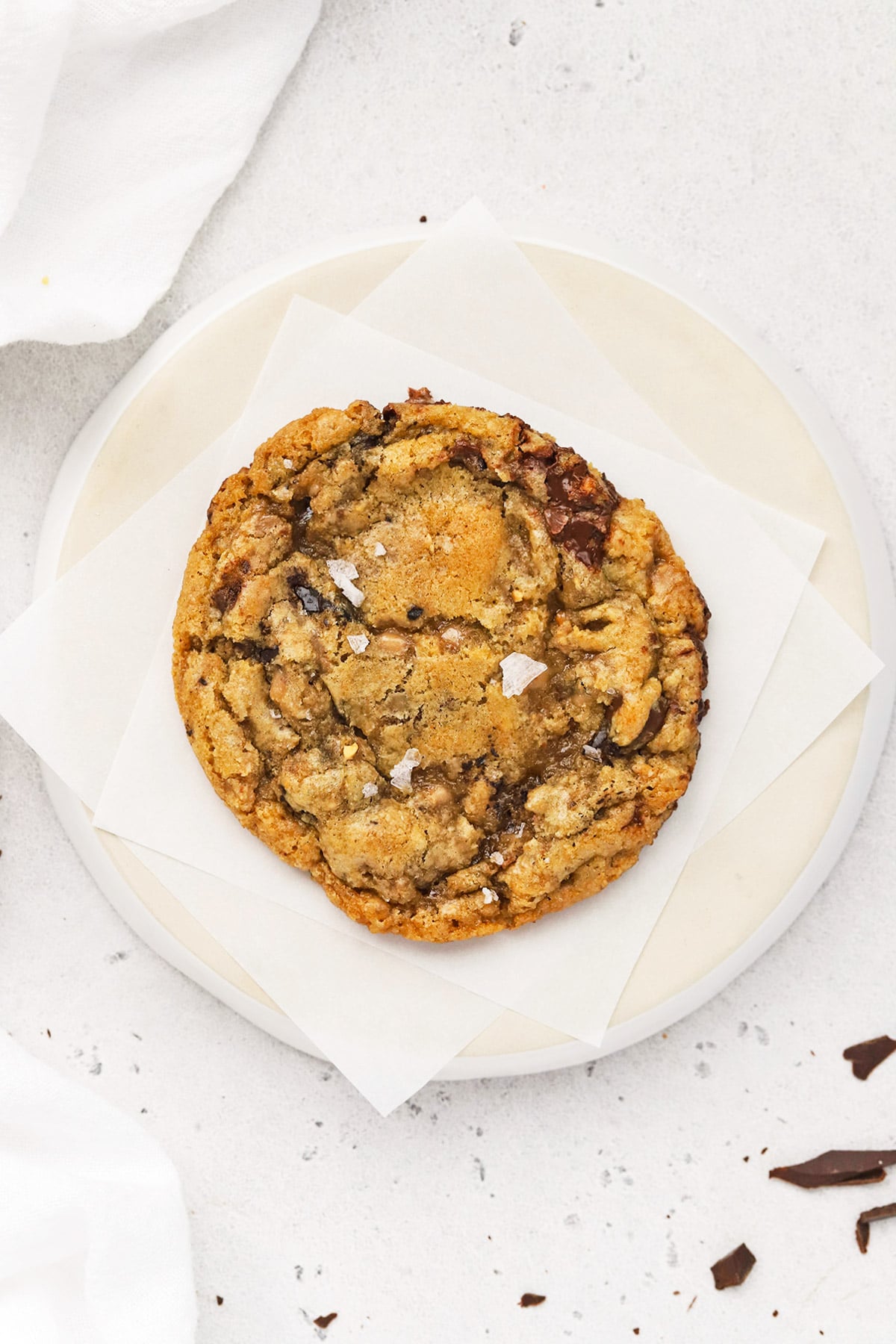 Overhead view of a golden gluten-free brown butter toffee chocolate chip cookie on a plate
