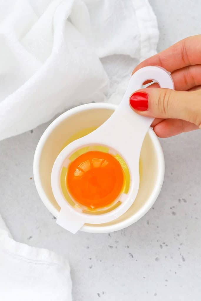 Overhead view of using an egg separator to separate egg yolks and egg whites