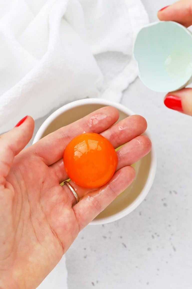 Overhead view of using your hand to separate egg yolks and egg whites