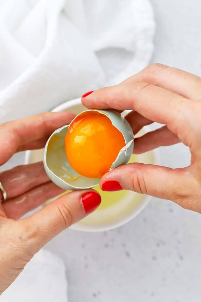 Overhead view of using an egg shell to separate egg yolks and egg whites