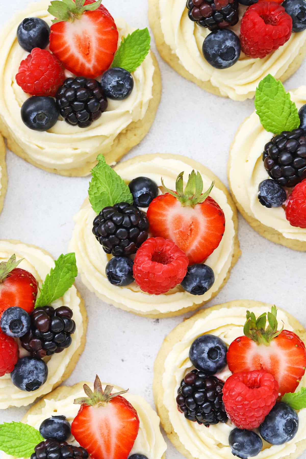 Overhead view of gluten-free fruit pizza cookies topped with cream cheese frosting and berries