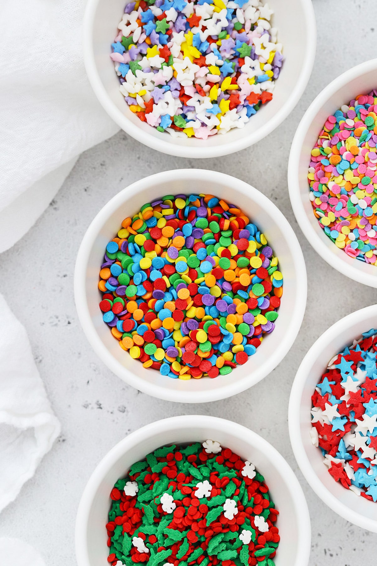 Different kinds of colorful quins sprinkles in white bowls