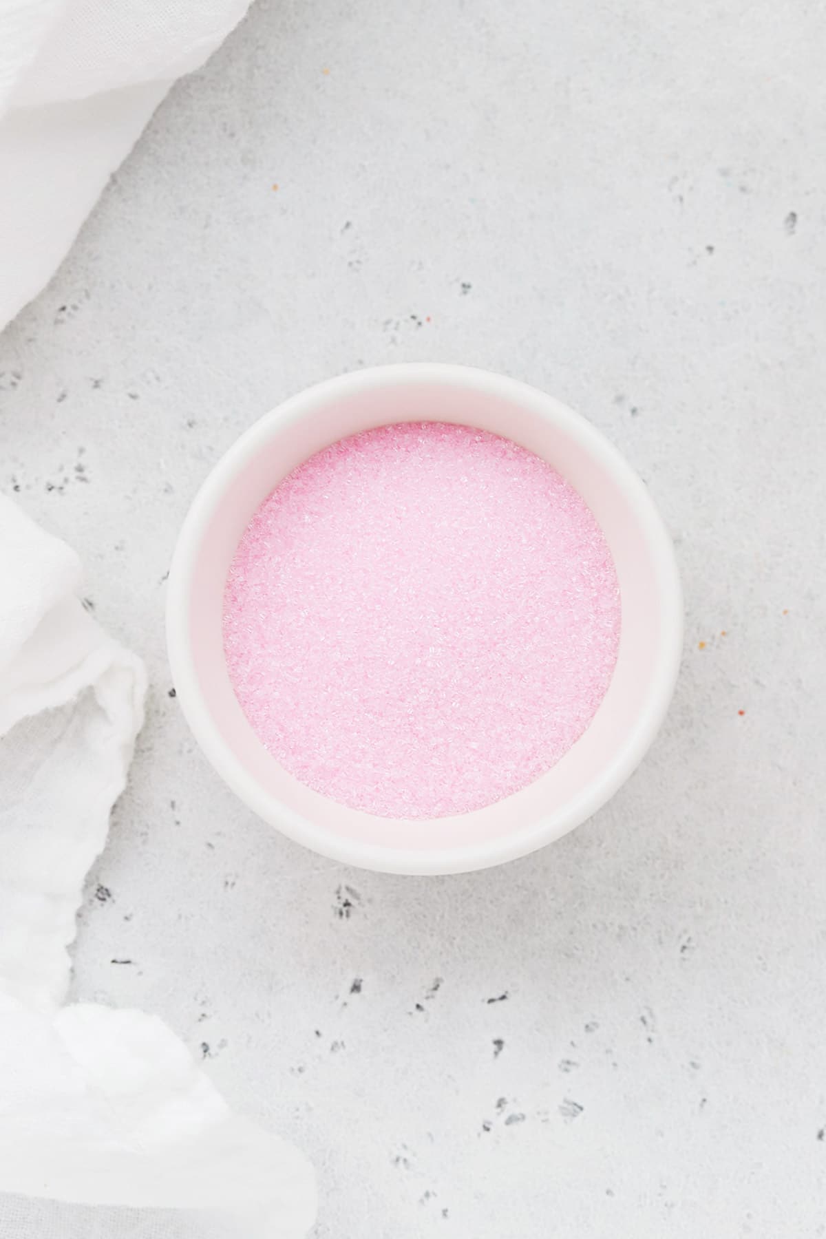 Soft pink sanding sugar sprinkles in a white bowl