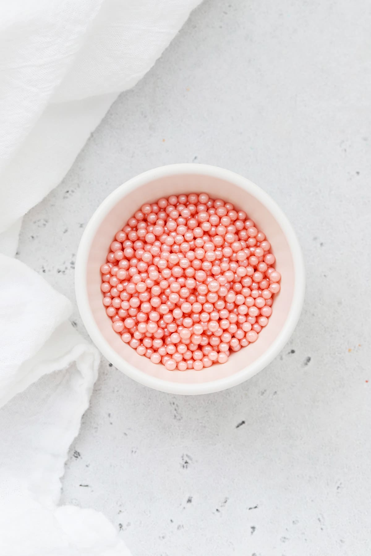 Pink sugar pearls sprinkles in a white bowl