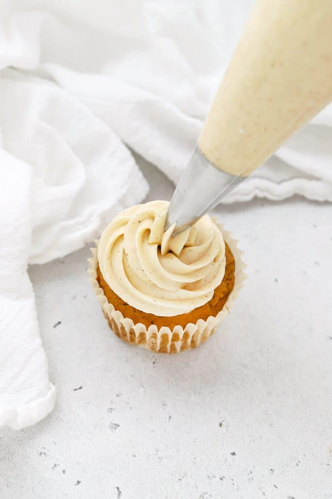 Frosting a gluten-free pumpkin cupcake with cinnamon cream cheese frosting