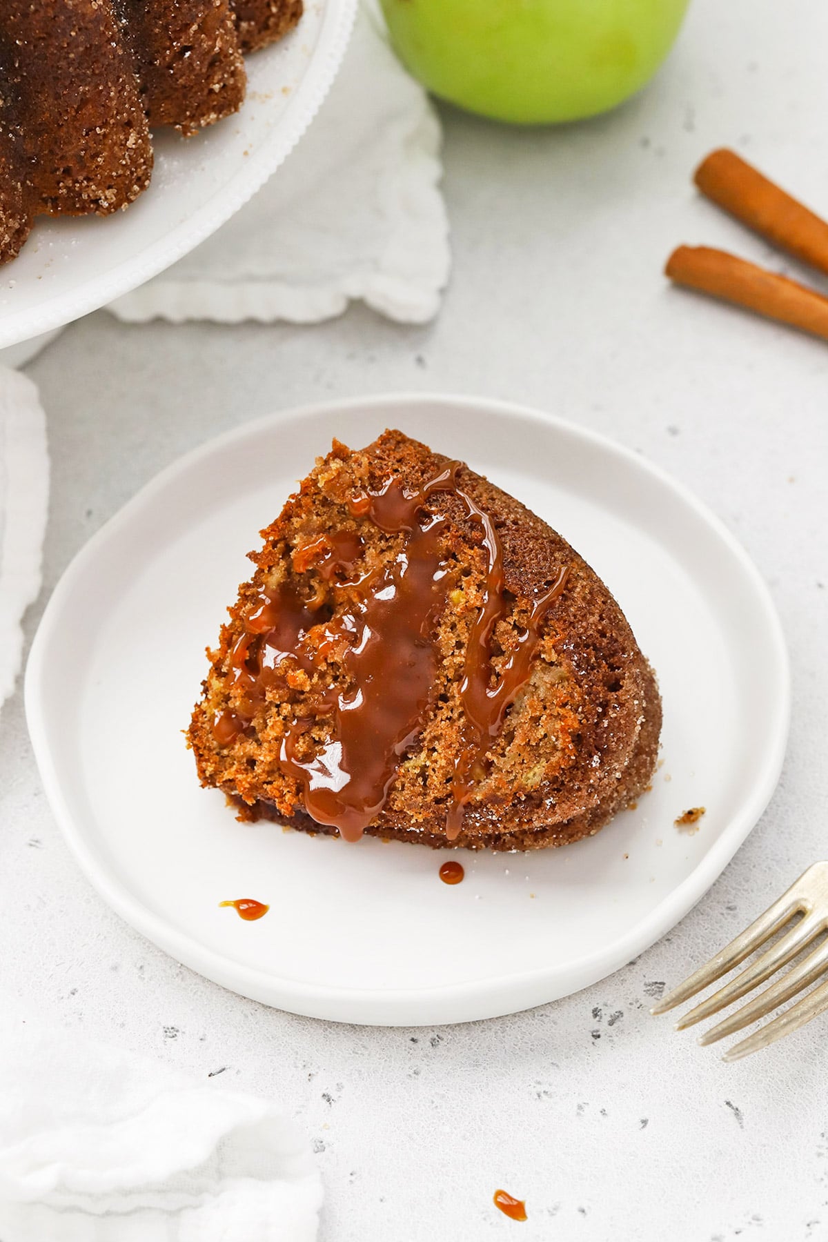 A slice of gluten-free apple spice bundt cake with caramel sauce drizzed on top