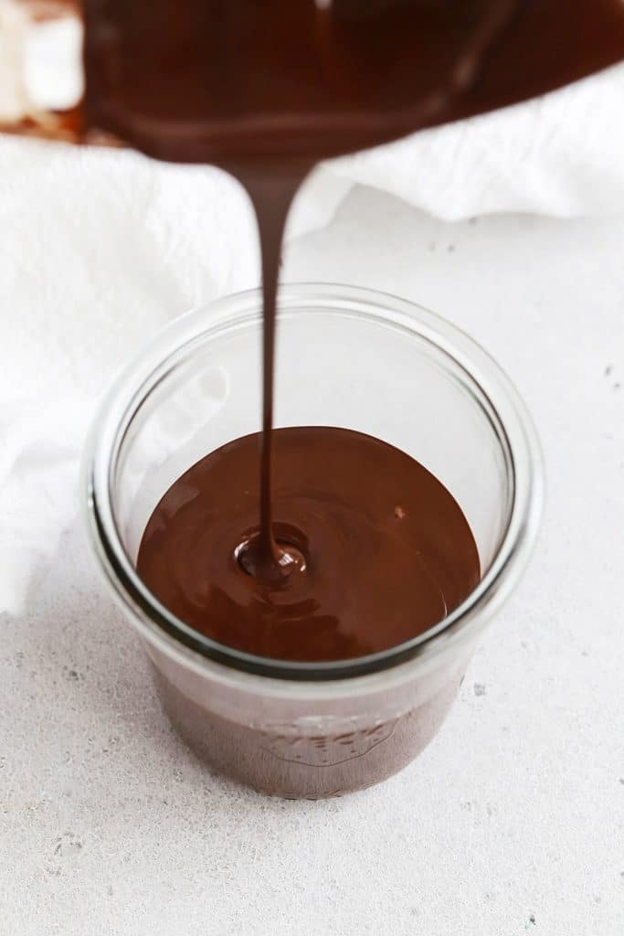 Pouring magic shell chocolate sauce into a jar 