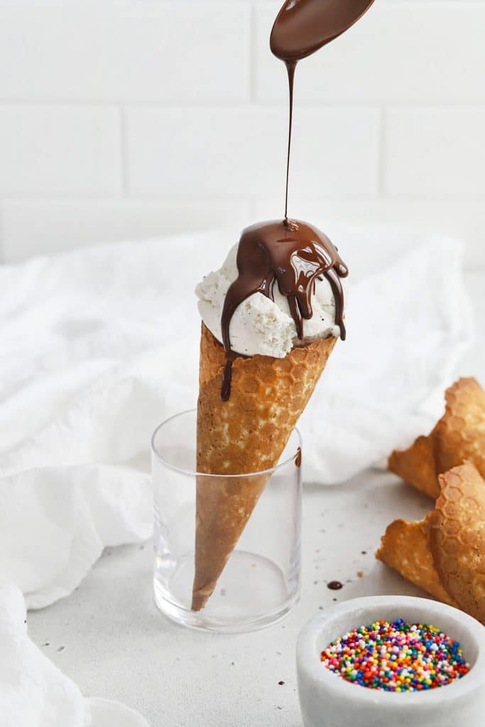Pouring homemade chocolate shell on a vanilla ice cream cone