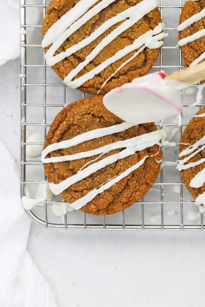 Drizzling melted white chocolate on a soft gluten-free ginger cookie