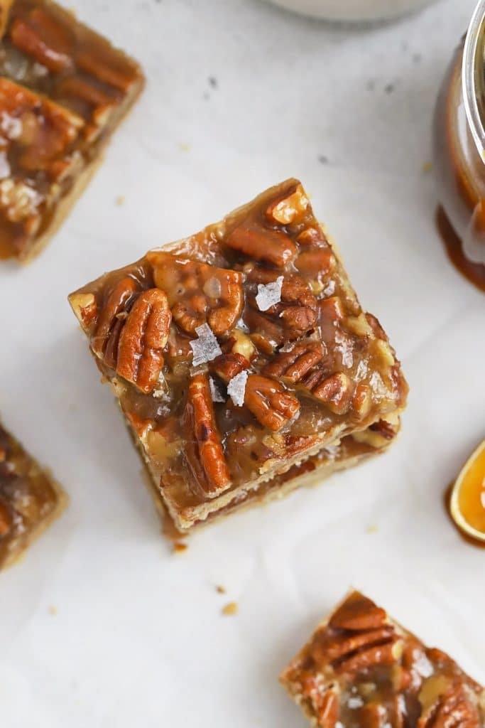 Overhead view of a stack of three gluten-free salted caramel pecan bars with brown sugar shortbread crust