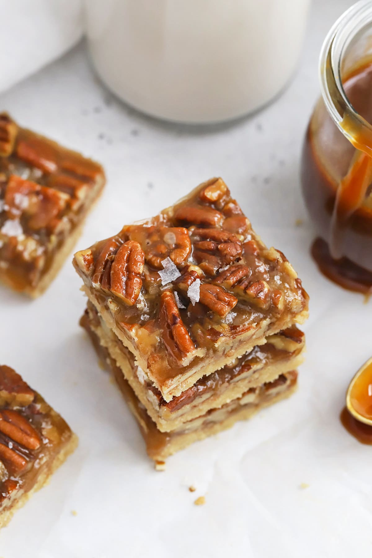 Front view of a stack of three gluten-free salted caramel pecan bars with brown sugar shortbread crust
