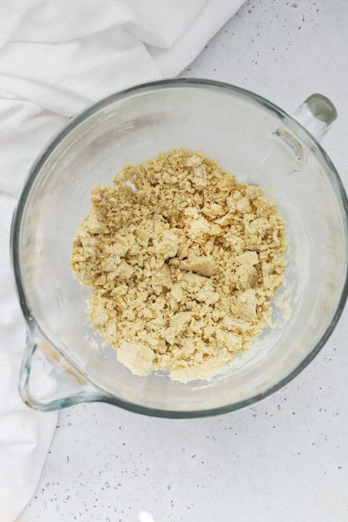 Overhead view of a mixing bowl with gluten-free crumbly brown sugar shortbread crust ready to be put into a baking dish