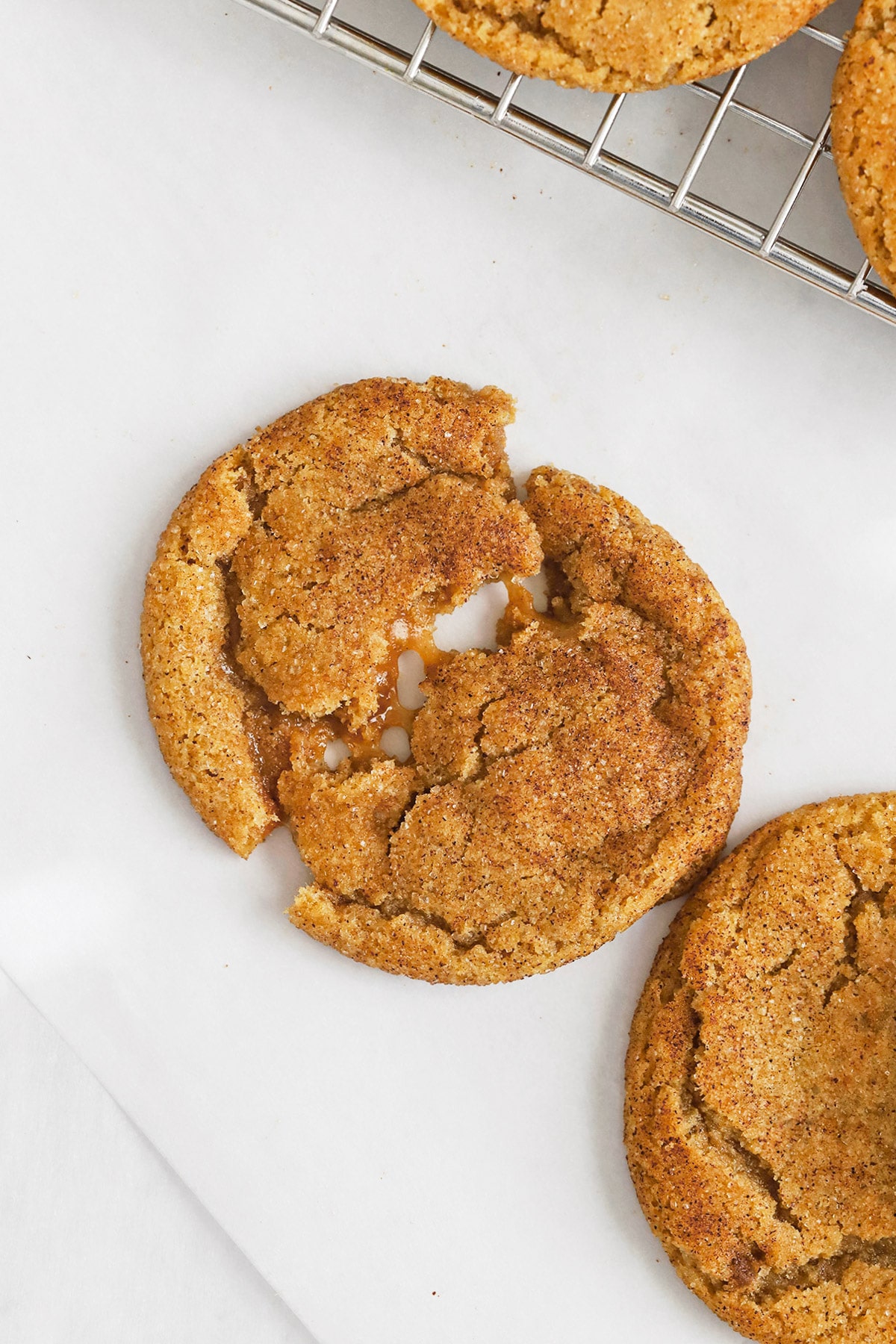 Pulling apart a gluten-free brown butter caramel snickerdoodle cookie, revealing gooey caramel in the center