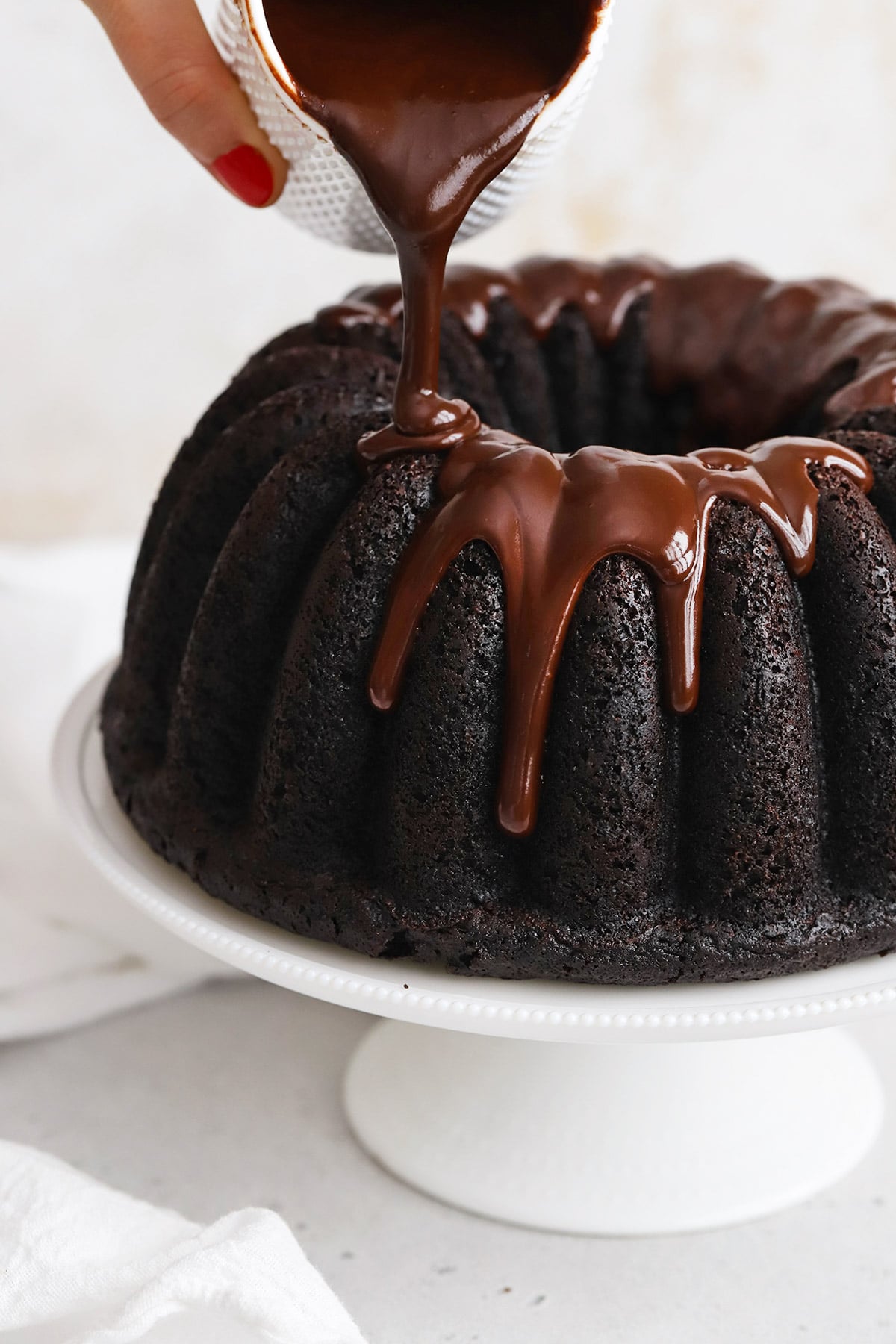 Front view of pouring chocolate glaze on a chocolate bundt cake