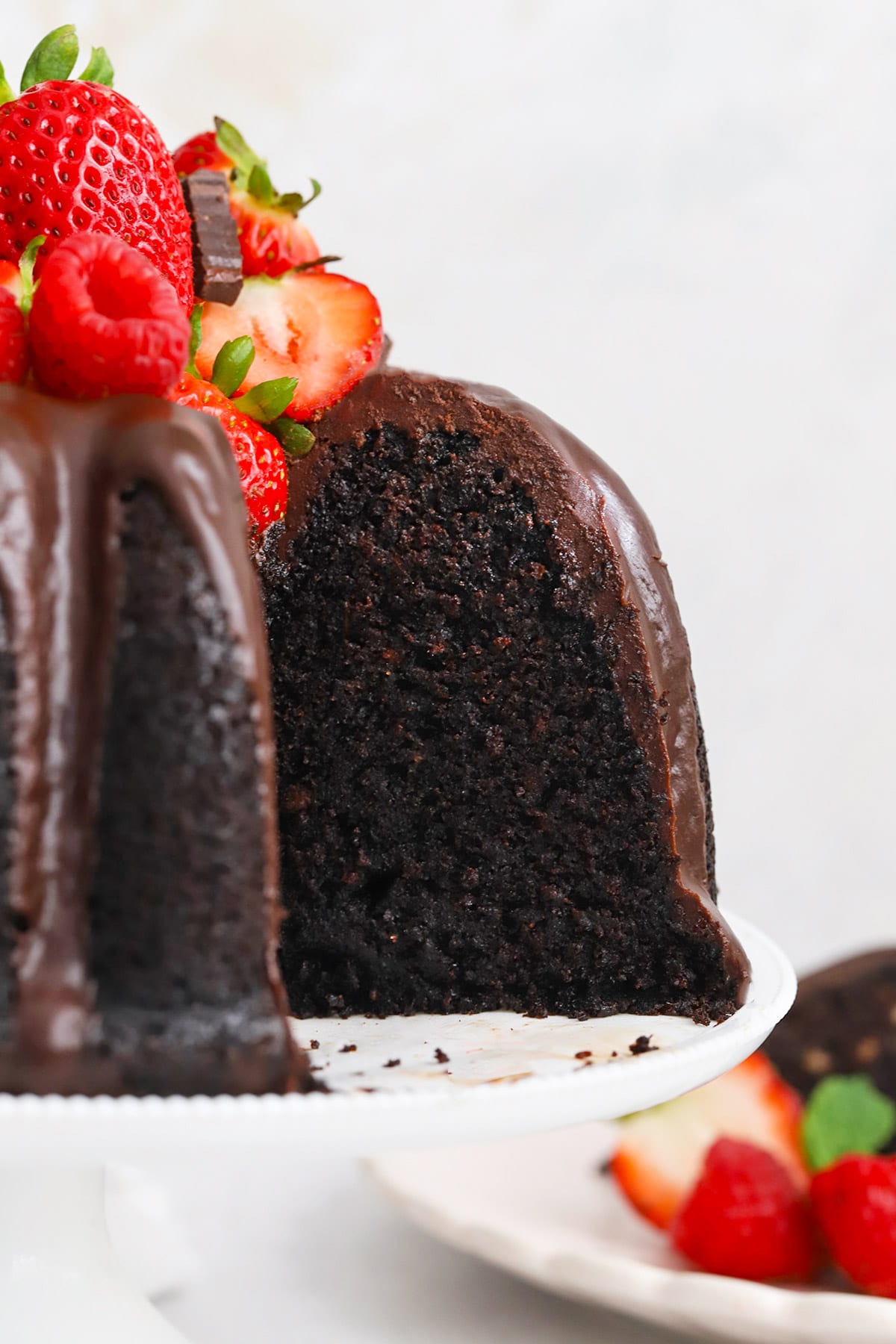 Front view of a chocolate bundt cake with a slice out of it, revealing a tender, perfectly cooked center