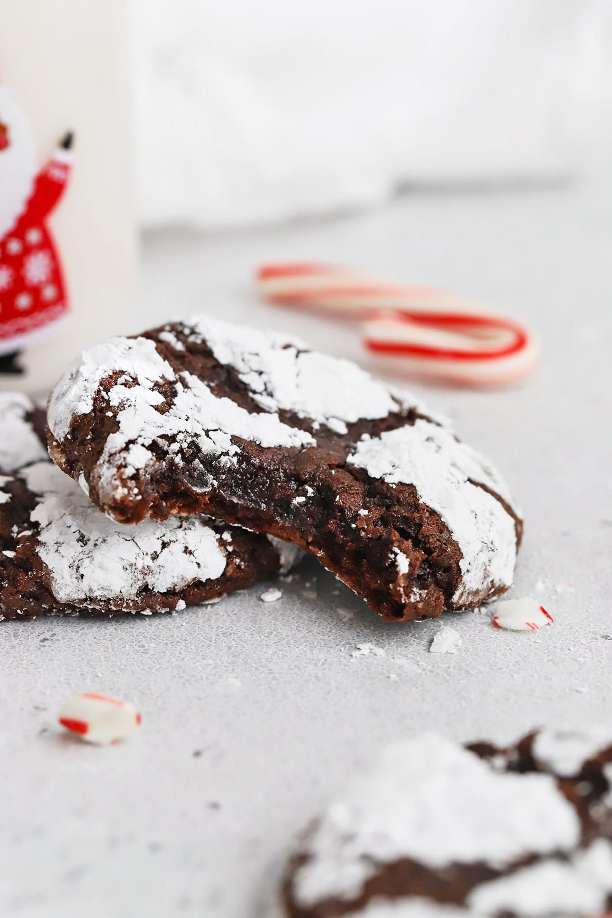 Front view of gluten-free peppermint chocolate crinkle cookies. One cookie has a bite out of it revealing a fudgy center.