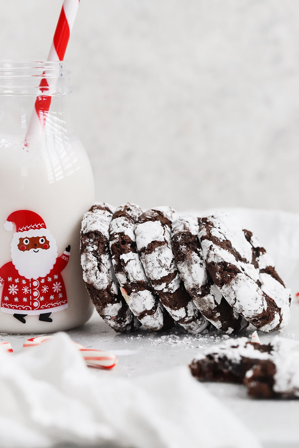 Front view of a stack of gluten-free peppermint chocolate crinkle cookies leaning on a bottle of milk