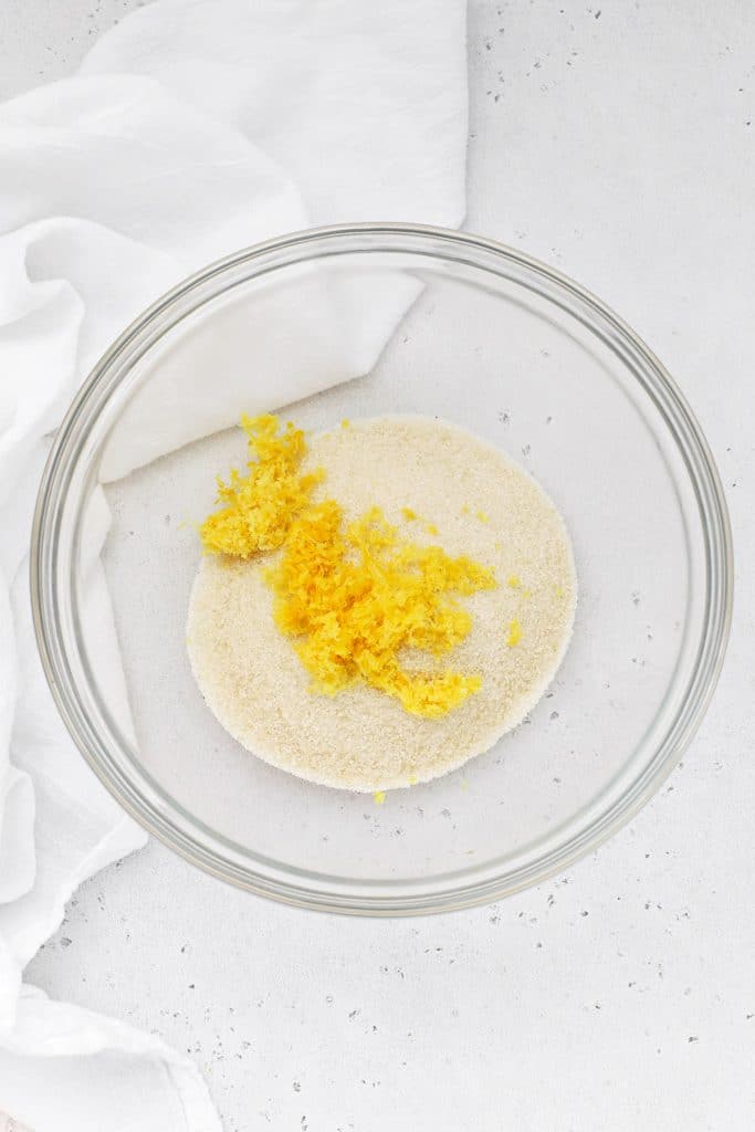 Lemon zest on top of sugar in a glass bowl