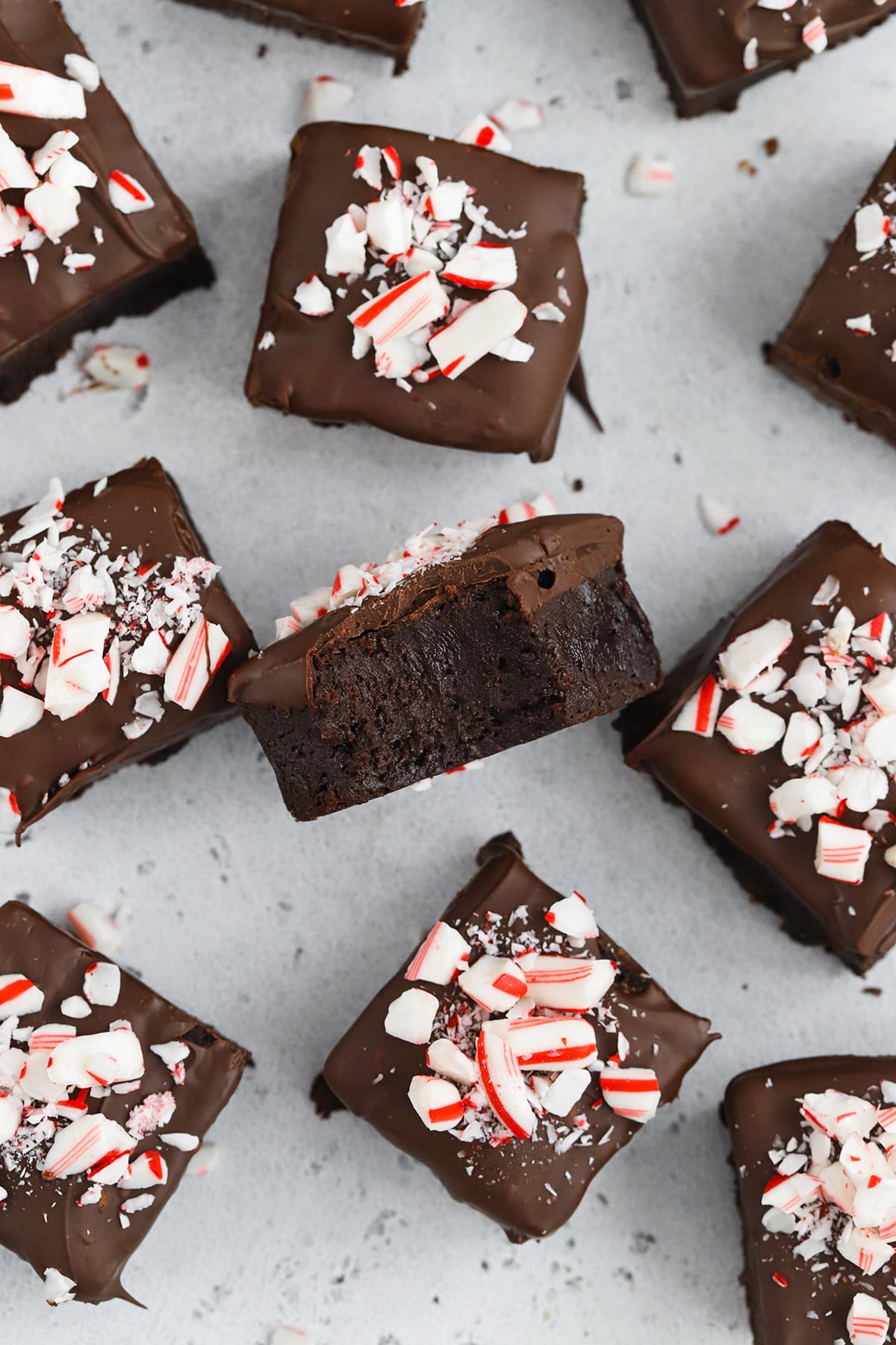 Overhead view of gluten-free peppermint brownie bites topped with crushed candy canes, one brownie bite is facing upward, revealing a fudgy center