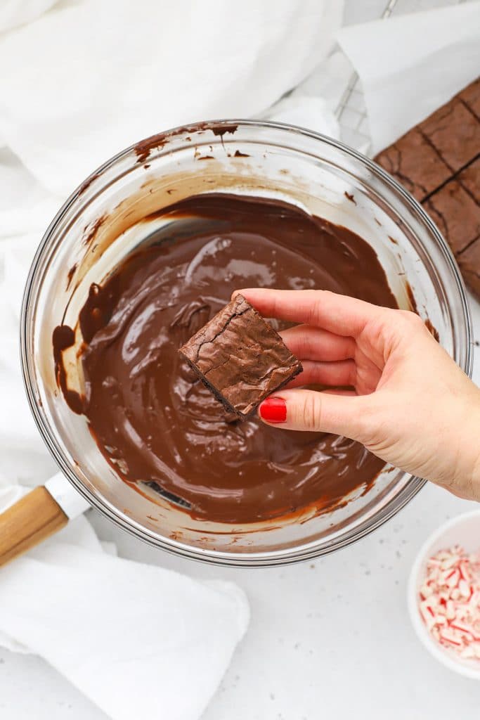 Dipping gluten-free peppermint brownie bites in melted chocolate