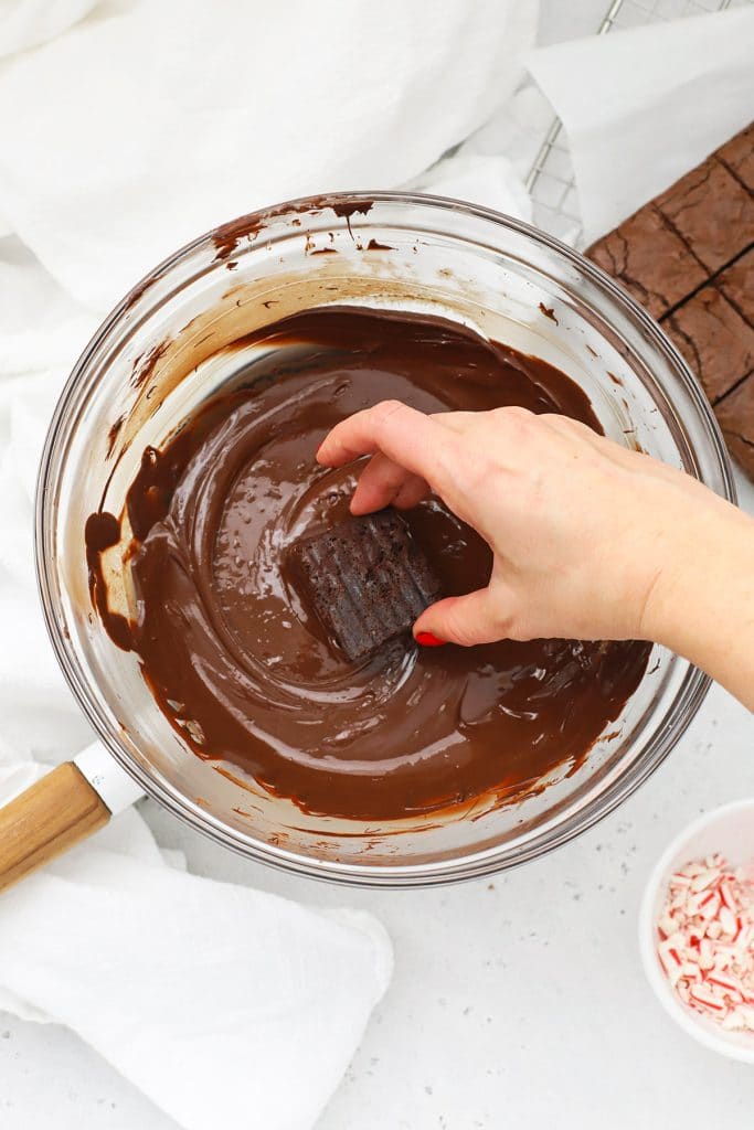 Dipping gluten-free peppermint brownie bites in melted chocolate
