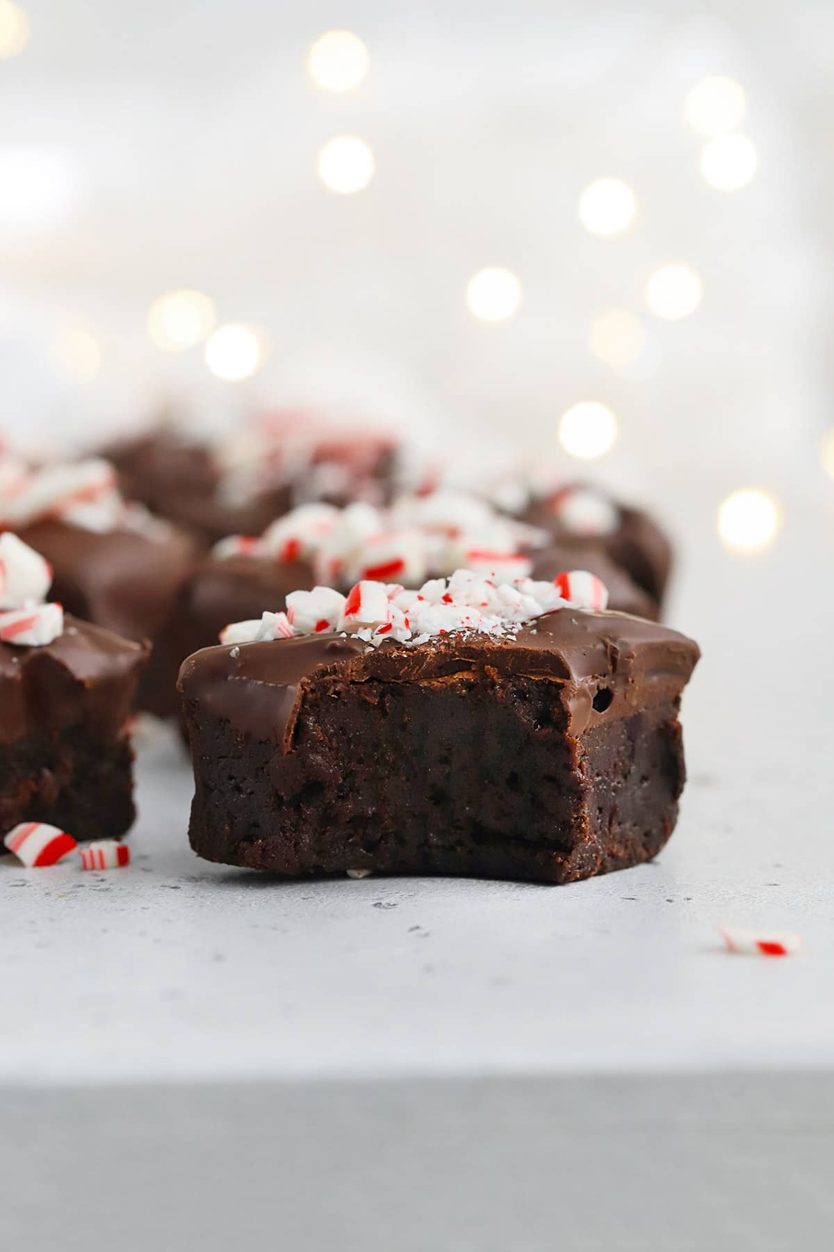 Front view of gluten-free peppermint brownie bites. One brownie bite has a bite taken out of it, revealing a fudgy center