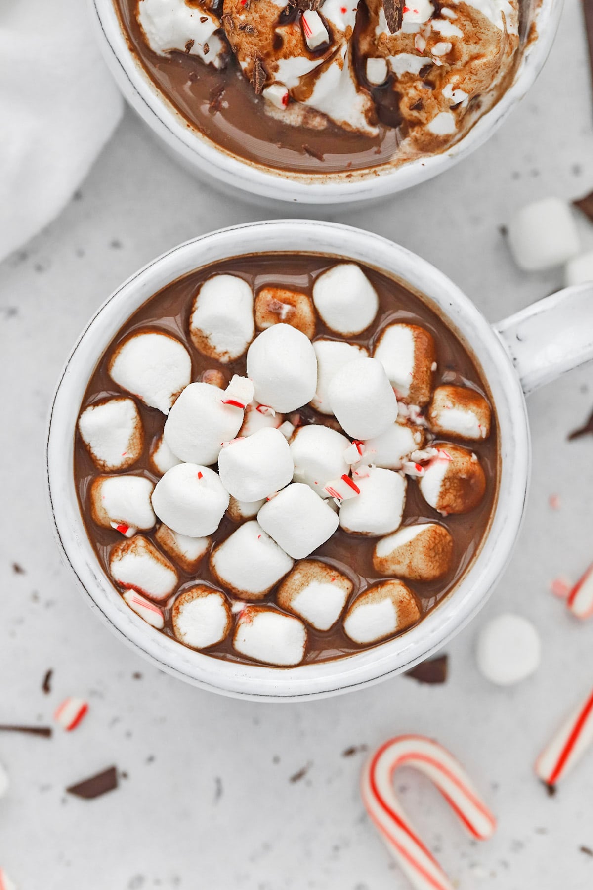 Overhead view of a steaming mug of vegan peppermint hot chocolate topped with marshmallows from Sweets & Thank You