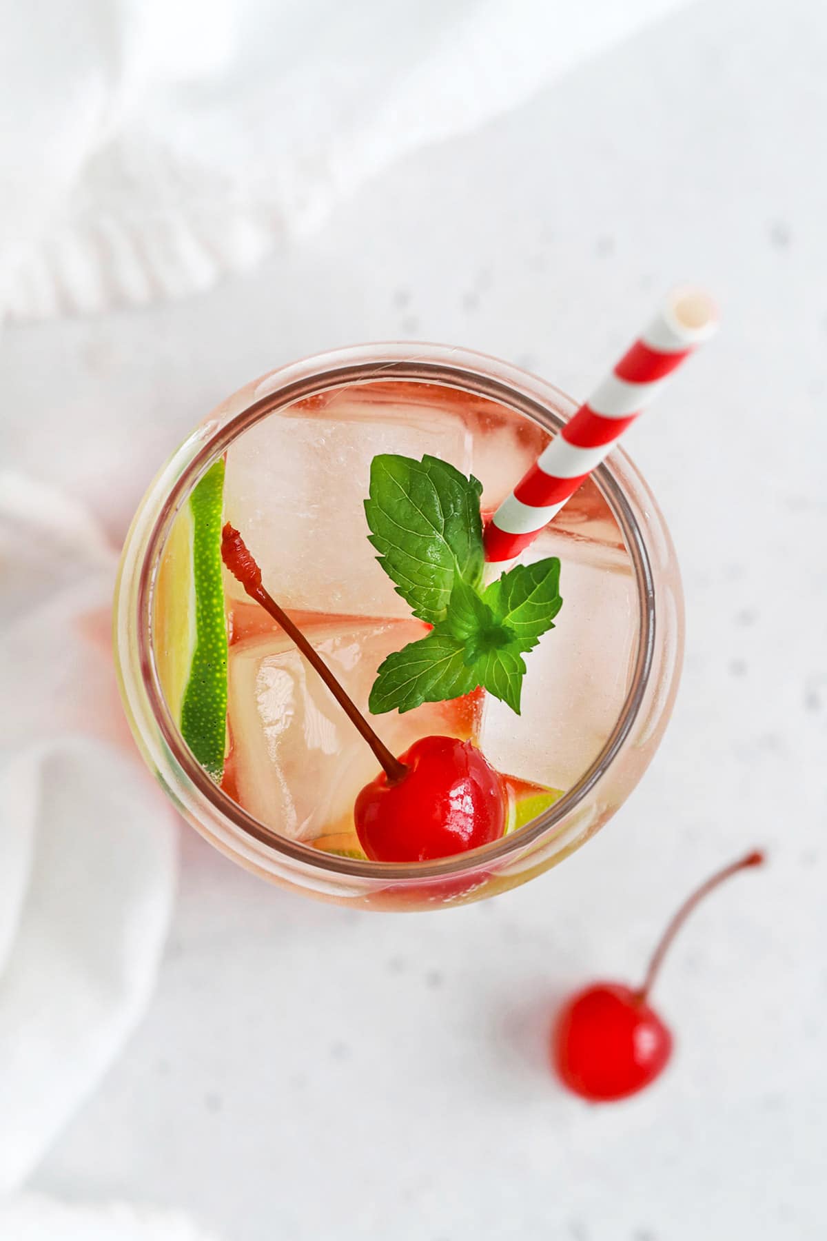 Overhead view of a classic shirley temple drink garnished with lime, cherry, and fresh mint