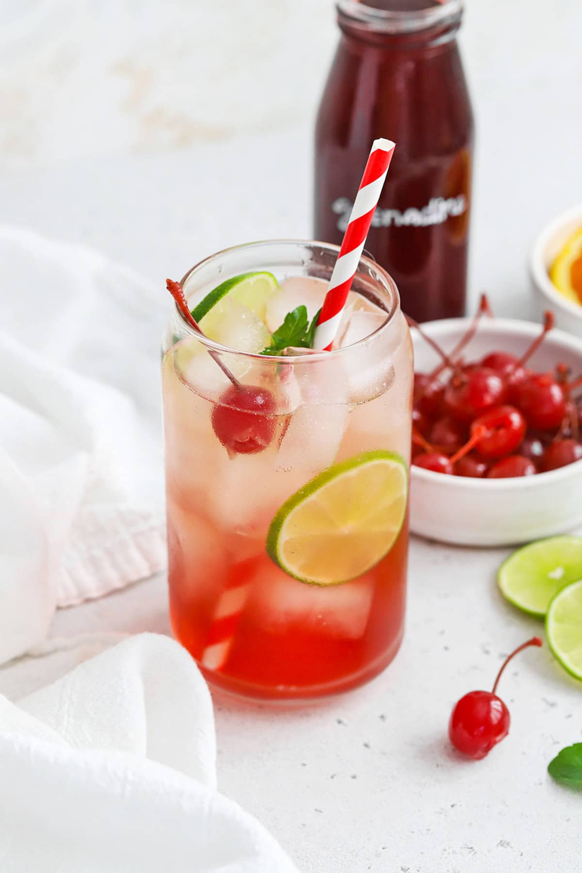 Front view of a classic shirley temple drink garnished with lime, cherry, and fresh mint