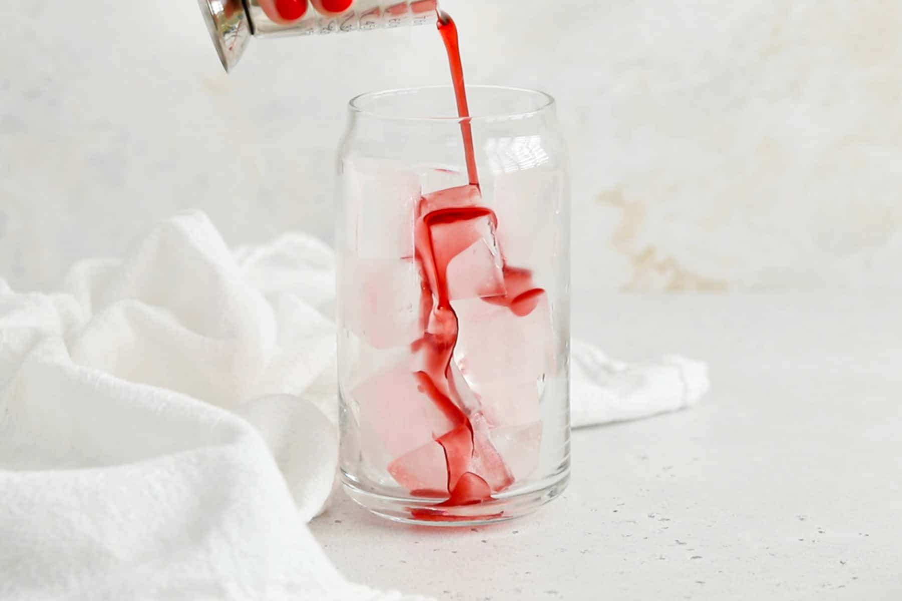 Pouring grenadine into a glass to make a classic shirley temple drink