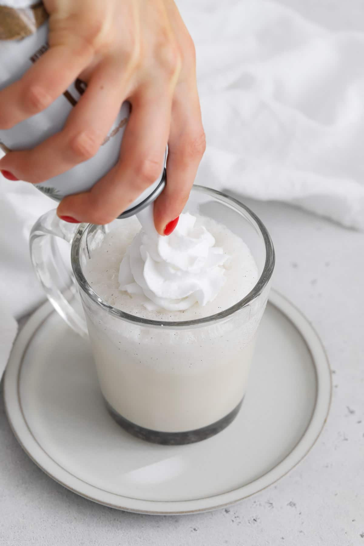 Putting whipped cream on a vanilla steamer