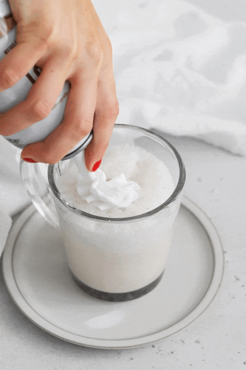 Putting whipped cream on a vanilla steamer