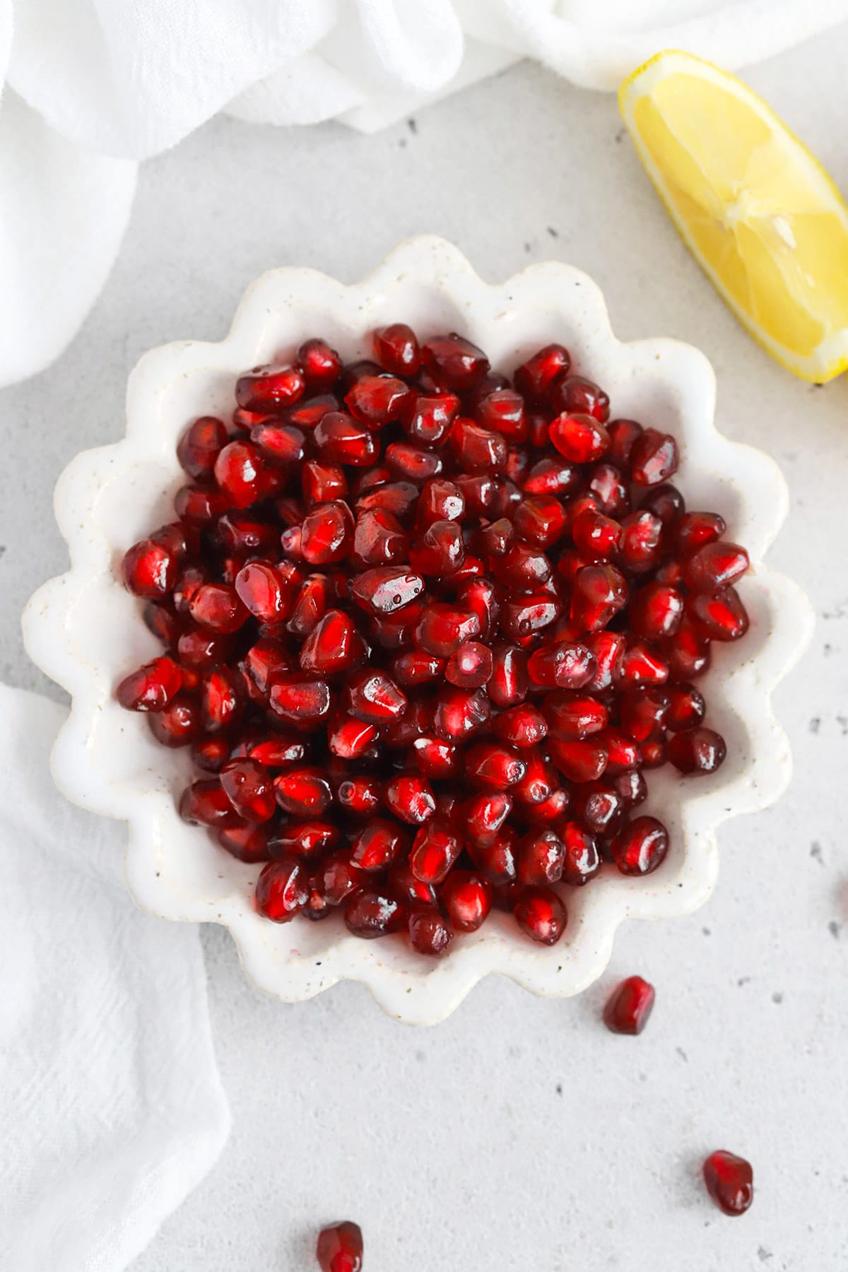 Overhead view of a ruffled white bowl of pomegranate arils