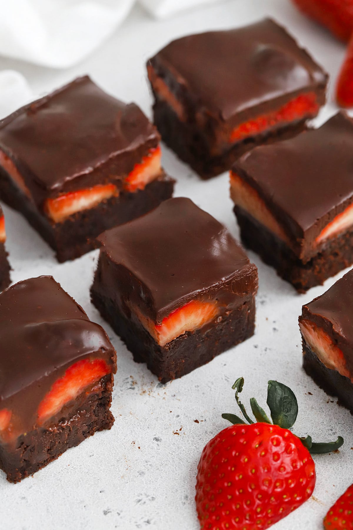 Front view of gluten-free strawberry brownies with fresh strawberries and chocolate ganache