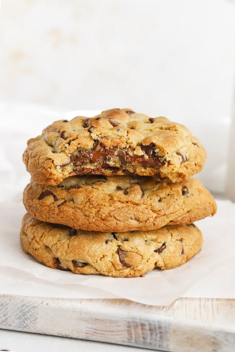 Front view of gluten-free Levain chocolate chip cookies stacked on top of each other, revealing a gooey middle