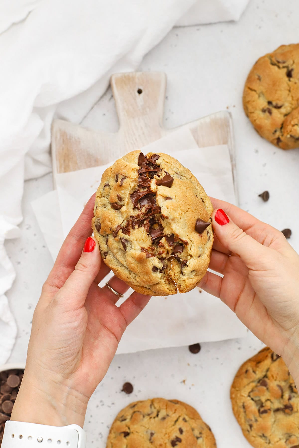 Breaking a gluten-free Levain chocolate chip cookie in half, revealing its gooey center