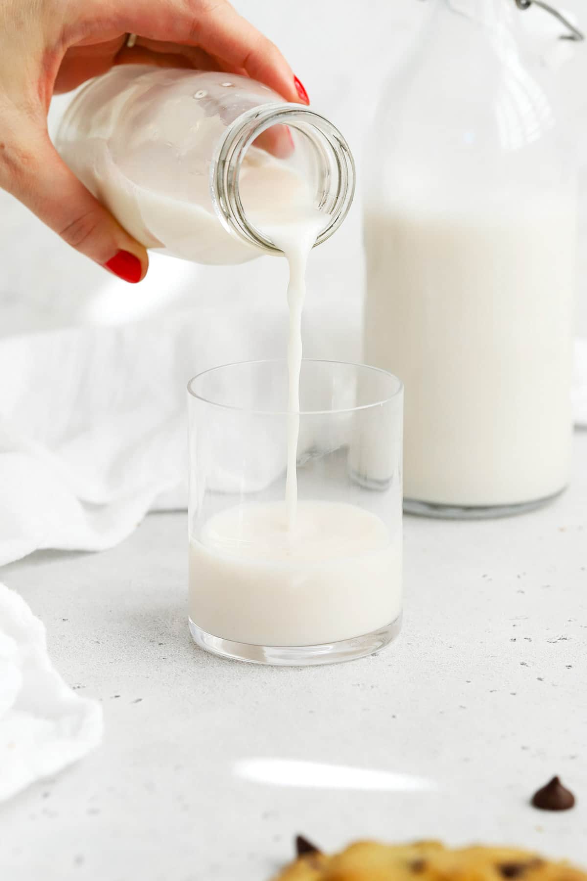 Pouring milk into a glass to go with thick gluten-free chocolate chip cookies