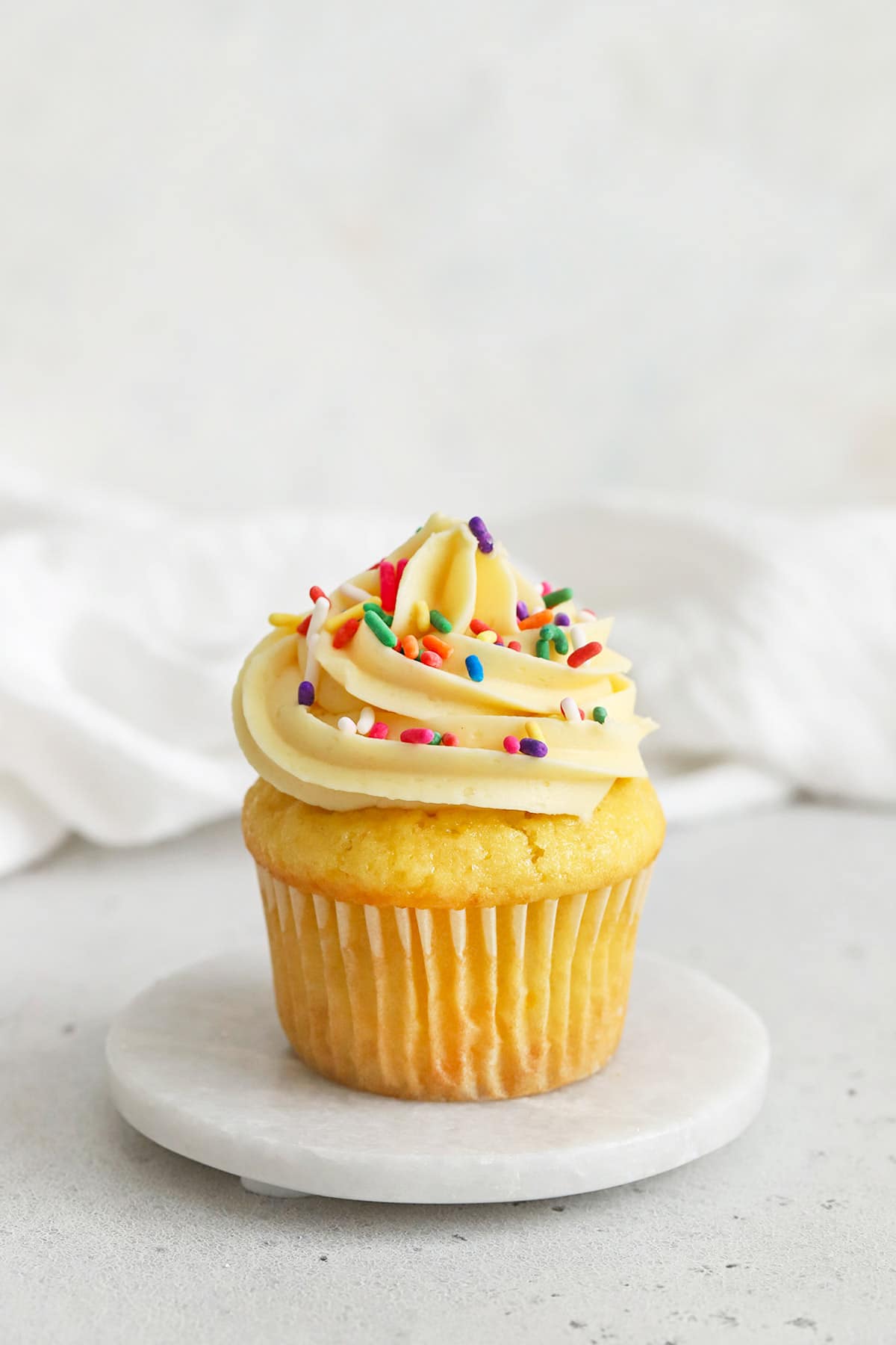 gluten-free vanilla cupcake topped with vanilla buttercream and jimmies sprinkles