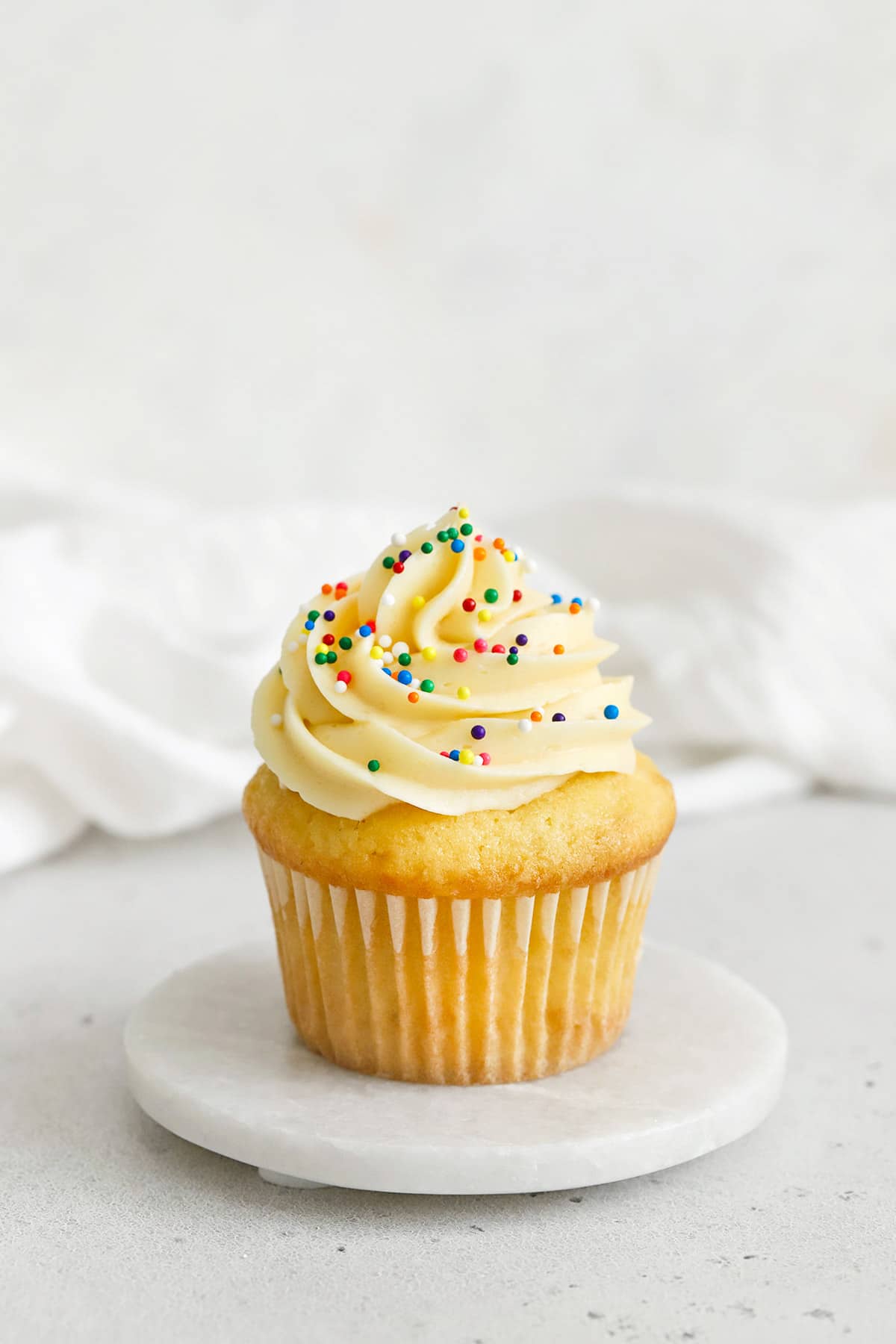 gluten-free vanilla cupcake topped with vanilla buttercream and nonpareils sprinkles