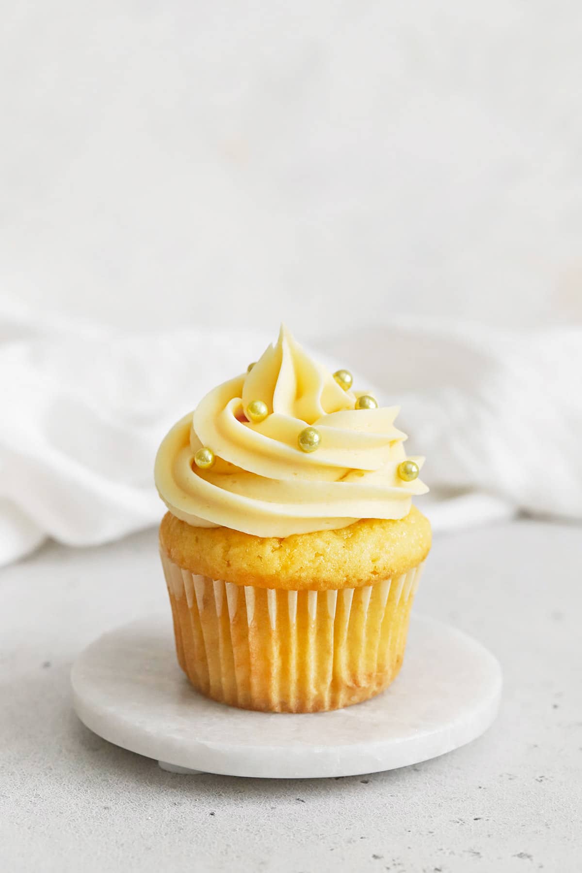 gluten-free vanilla cupcake topped with vanilla buttercream and gold dragees sprinkles