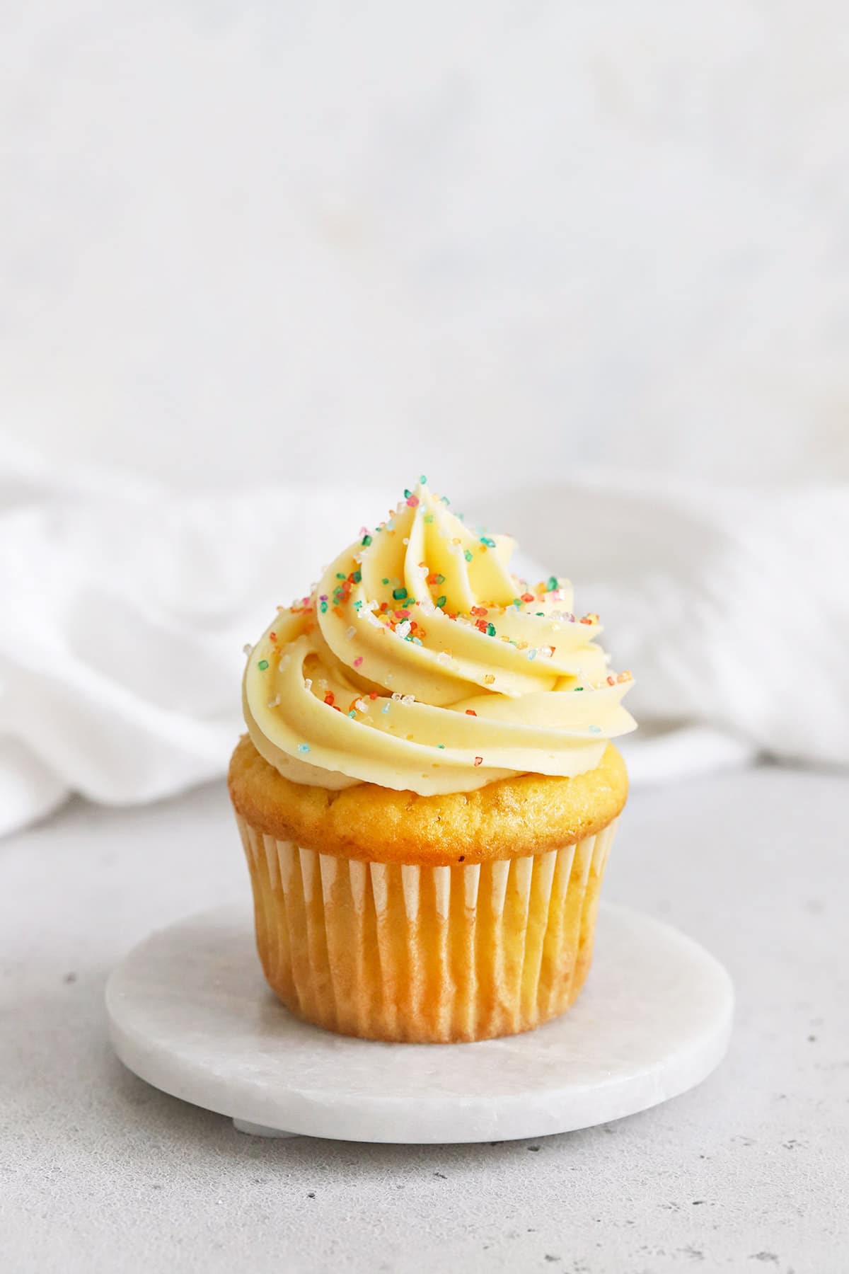 gluten-free vanilla cupcake topped with vanilla buttercream and multicolor sparkling sugar sprinkles