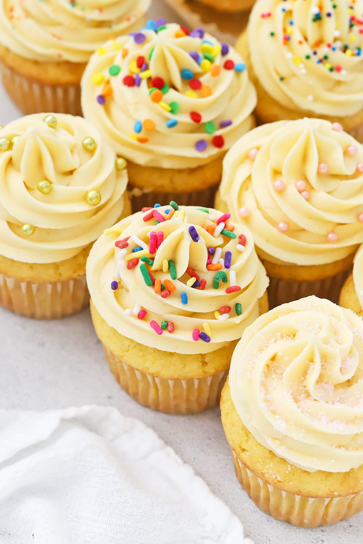 Front view of gluten-free vanilla cupcakes topped with vanilla buttercream and different kinds of sprinkles
