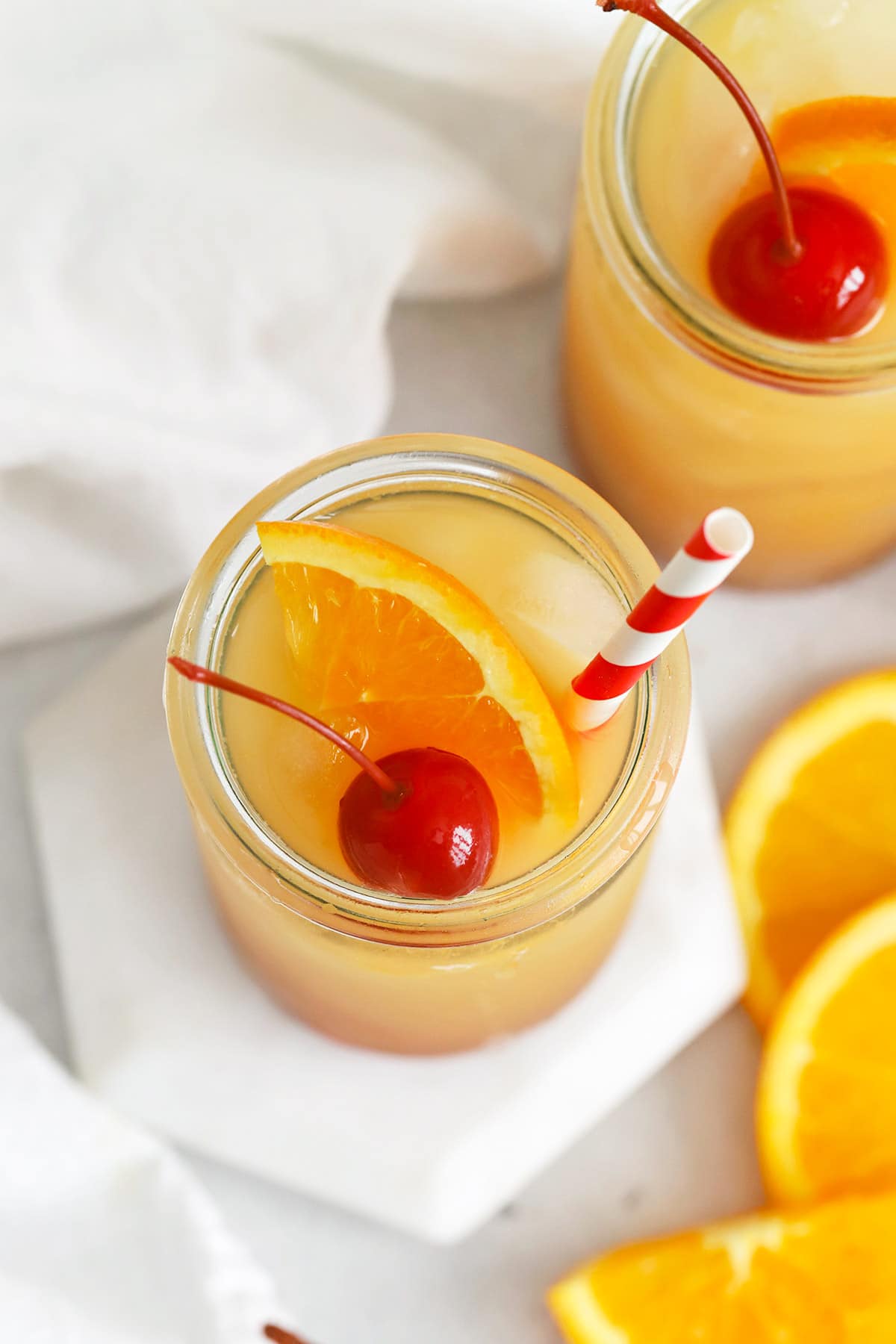 Front view of Sweets & Thank You Sweet Sunrise Mocktail garnished with orange and maraschino cherry
