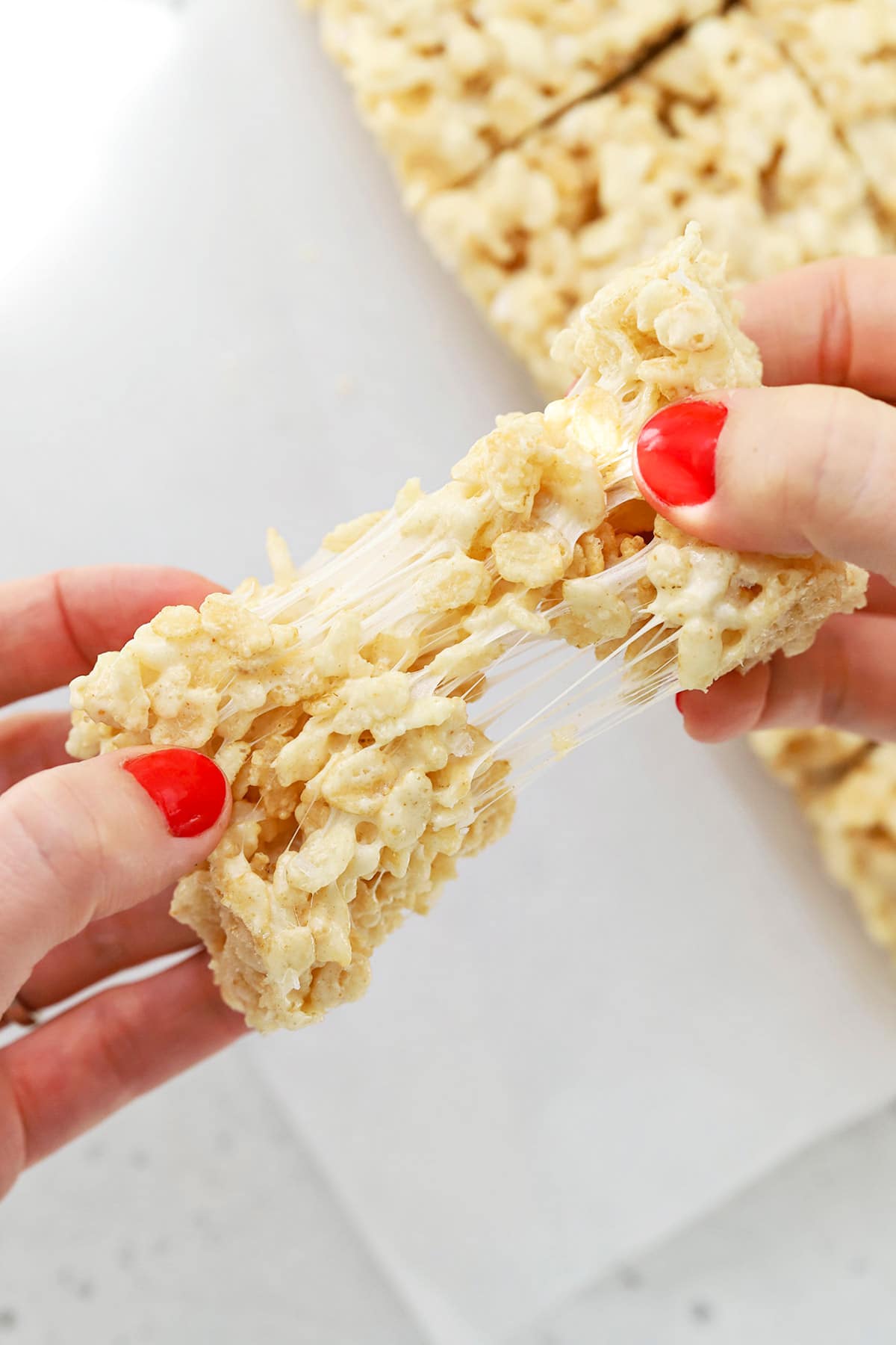 Pulling apart a gluten-free rice krispies treat, showing the gooey texture