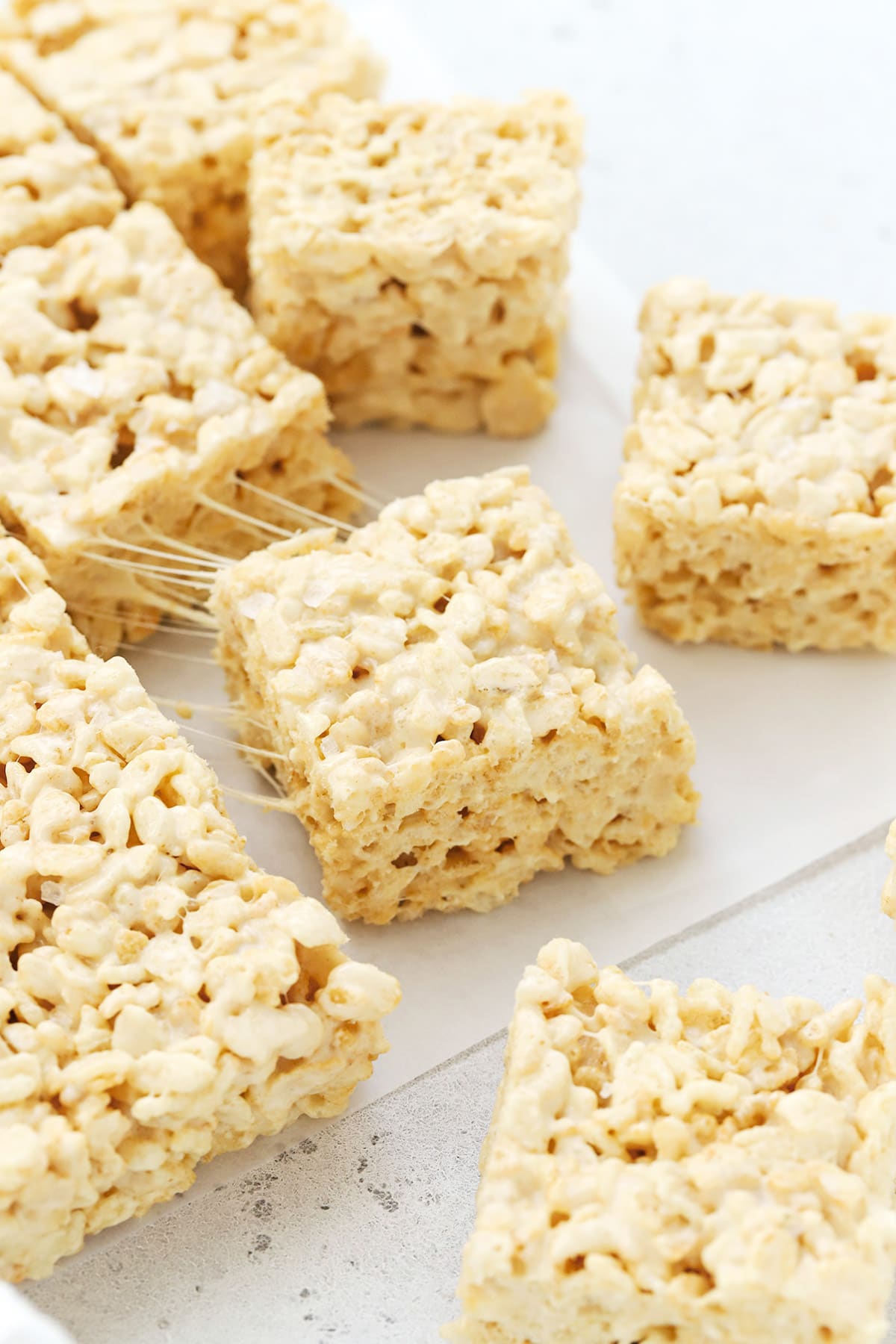 Pulling a square of gluten-free brown butter rice krispies treats away showing the gooey texture