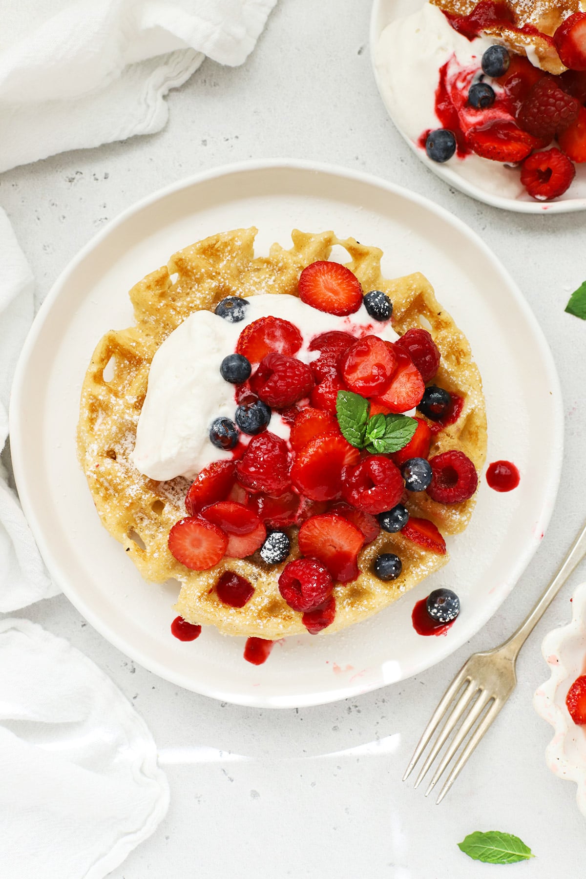 Overhead view of fluffy gluten-free Belgian waffles topped with whipped cream and berries