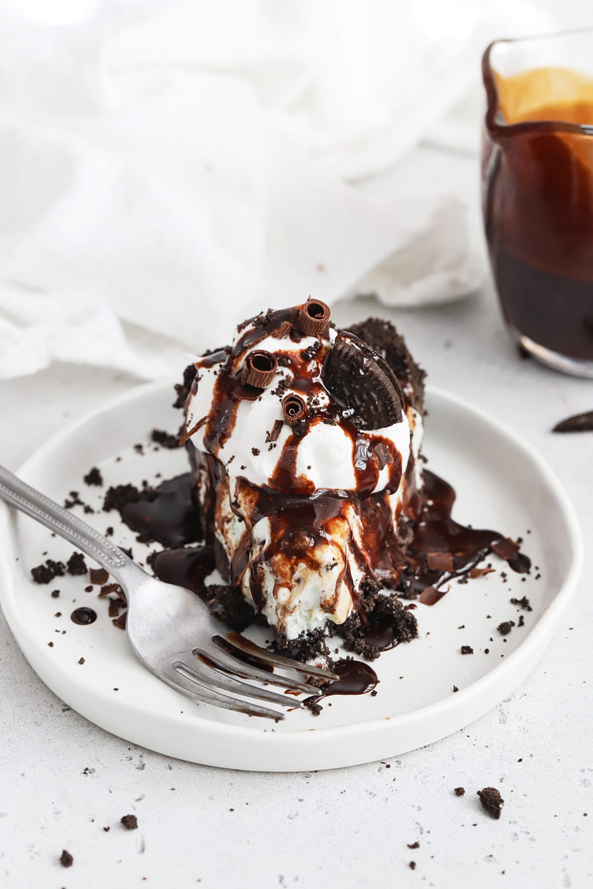Front view of a slice of gluten-free grasshopper pie topped with whipped cream and chocolate sauce