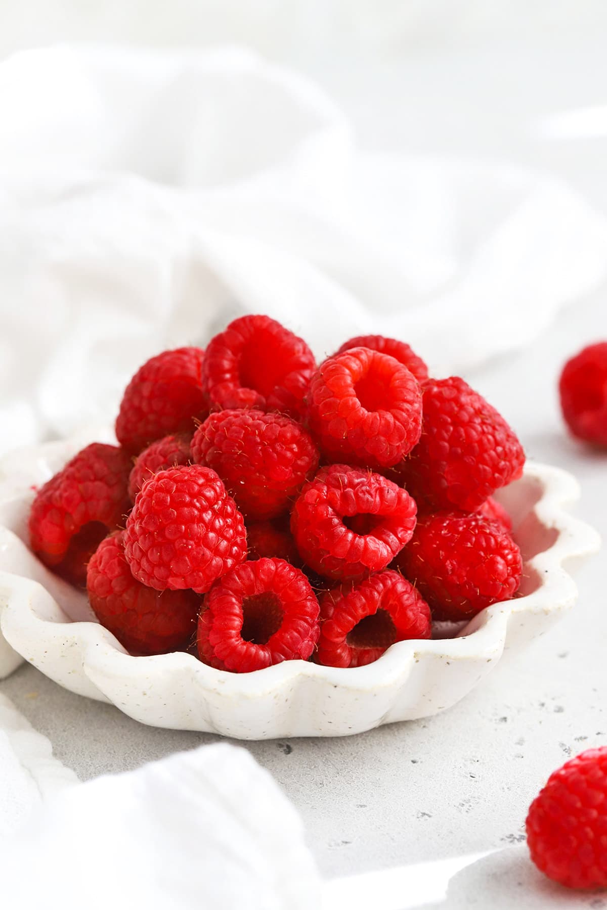 Front view of a ruffled white bowl of fresh raspberries