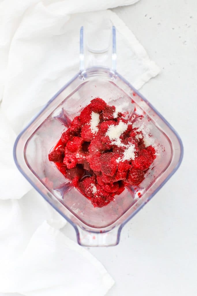 Overhead view of ingredients for fresh raspberry sauce in a blender